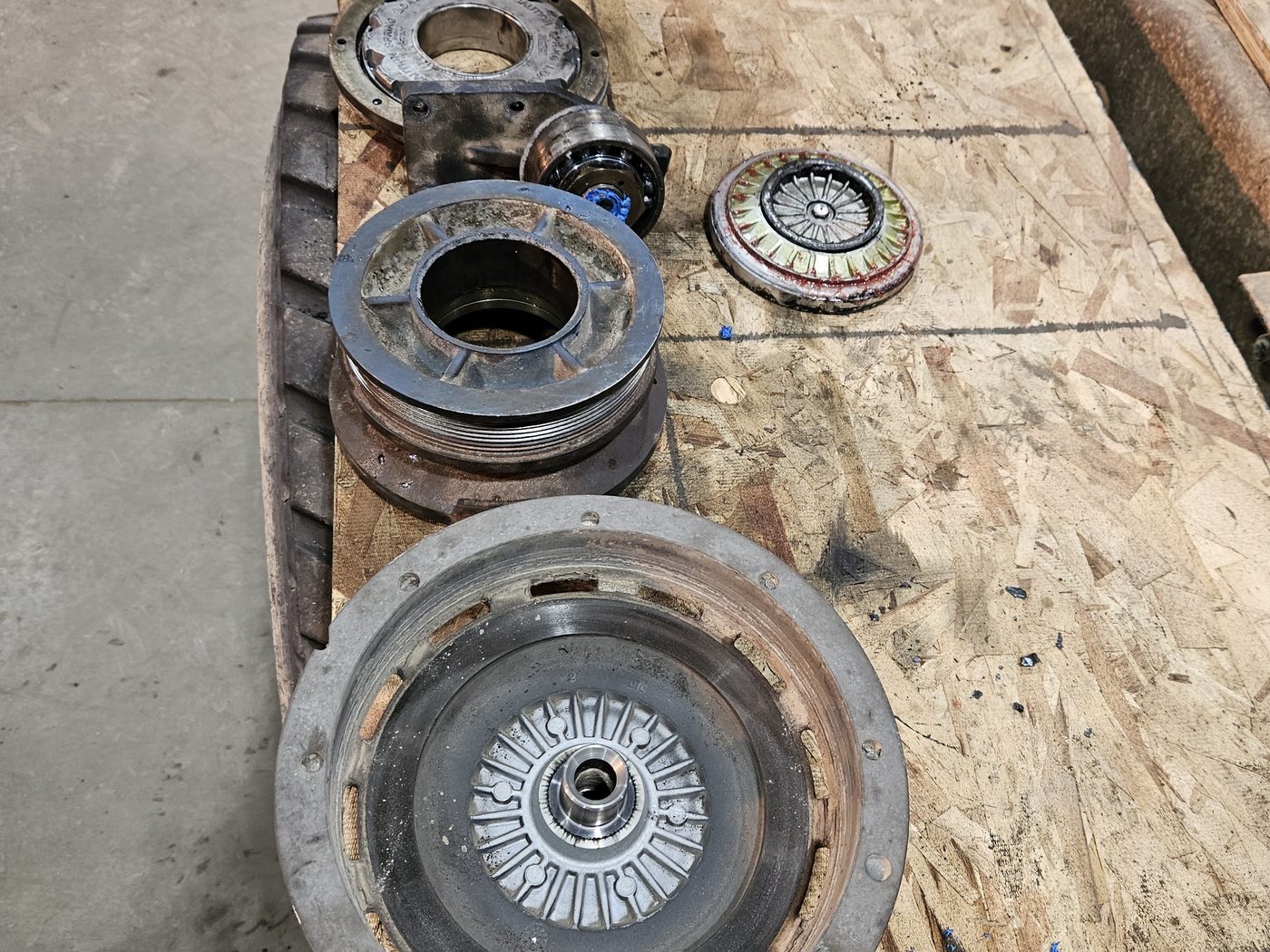 Clutch, flywheel and hub laid out on plywood during a clutch job