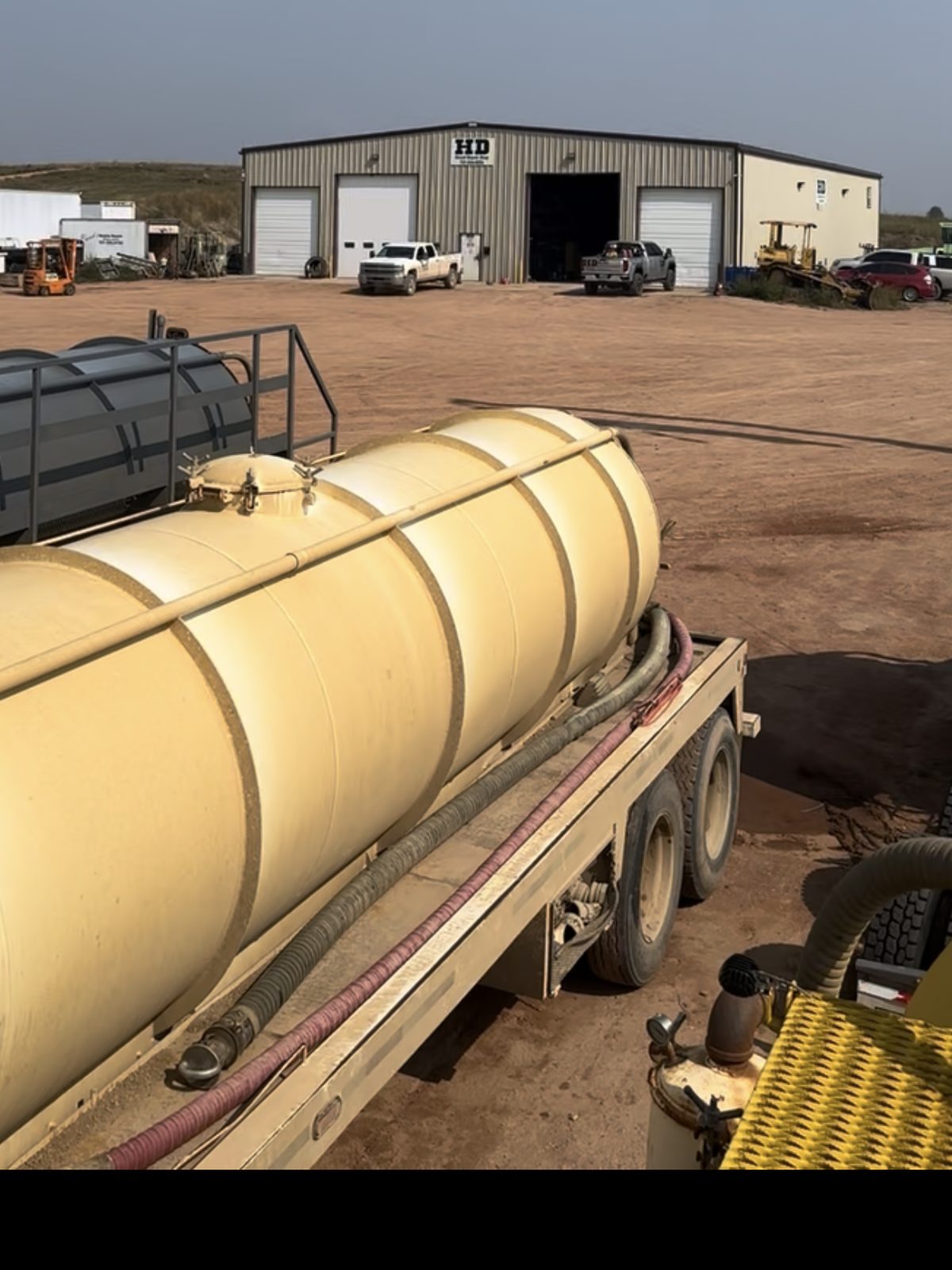 A tank trailer on the lot in front of the shop